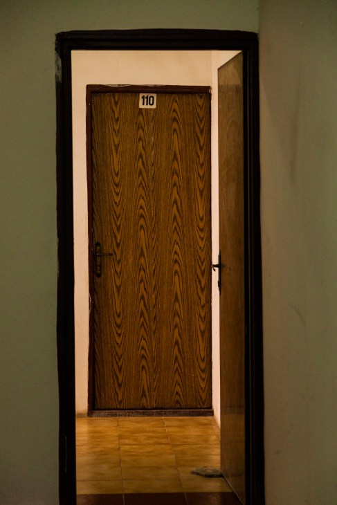 Hotel hallway with wood-paneled door numbered 110 viewed through open doorway.