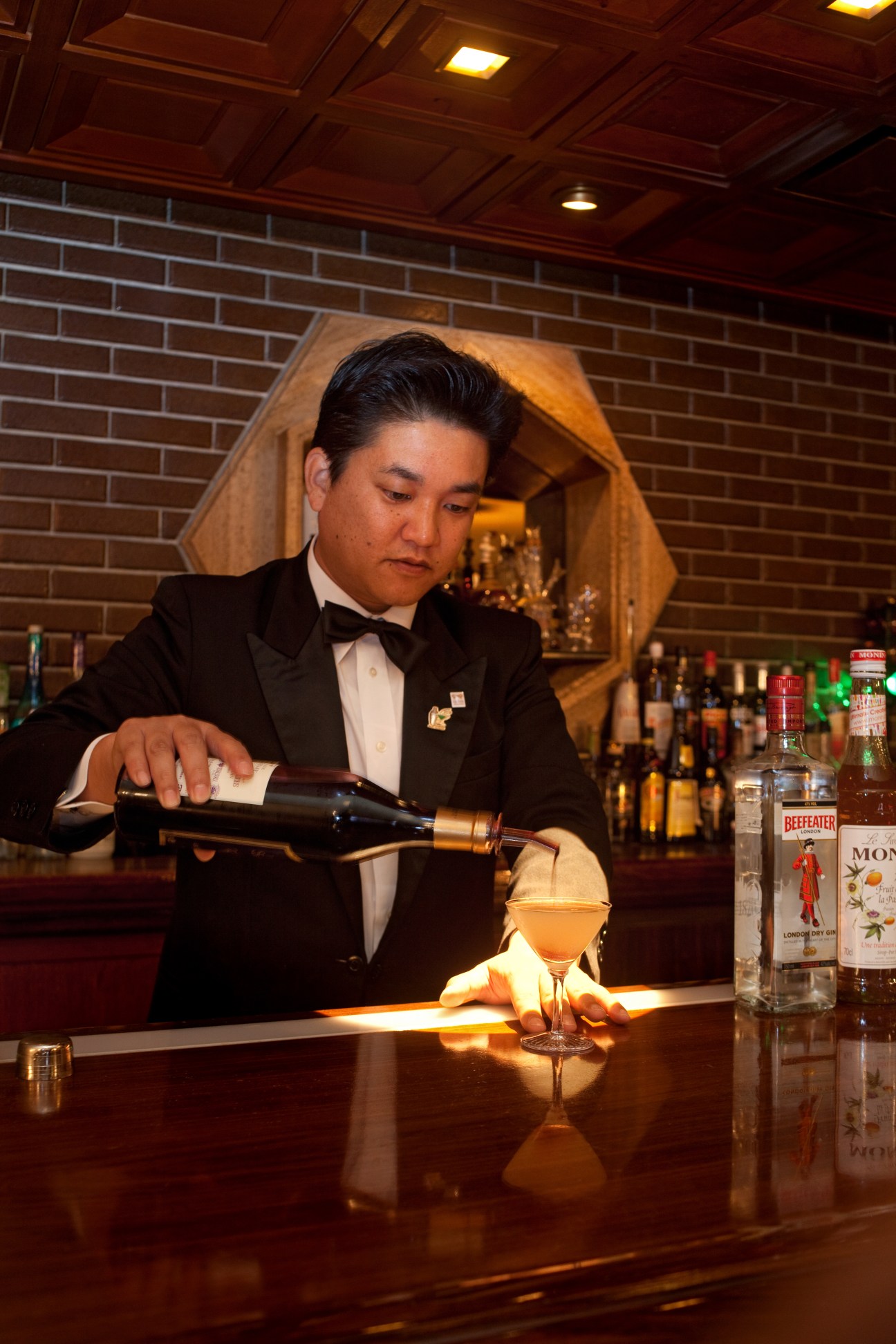 Yasuhiro Katsumata, chief bartender at Old Imperial Bar, pouring a cocktail behind the counter.