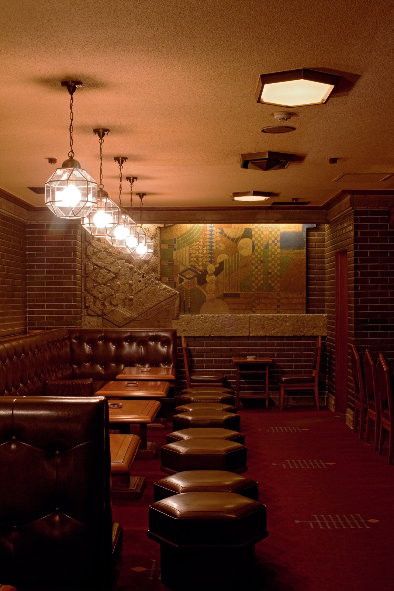 Interior of Old Imperial Bar showing pendant lights, brick walls, leather seating and stone backdrop.