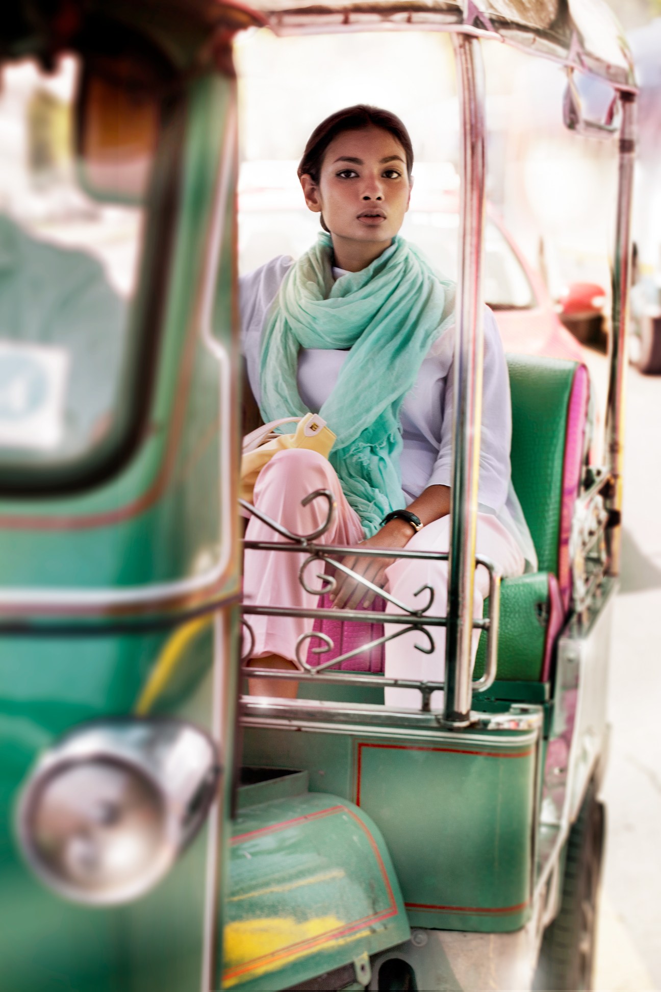 Woman in lavender shirt and green scarf sits in a colorful Bangkok tuk-tuk.