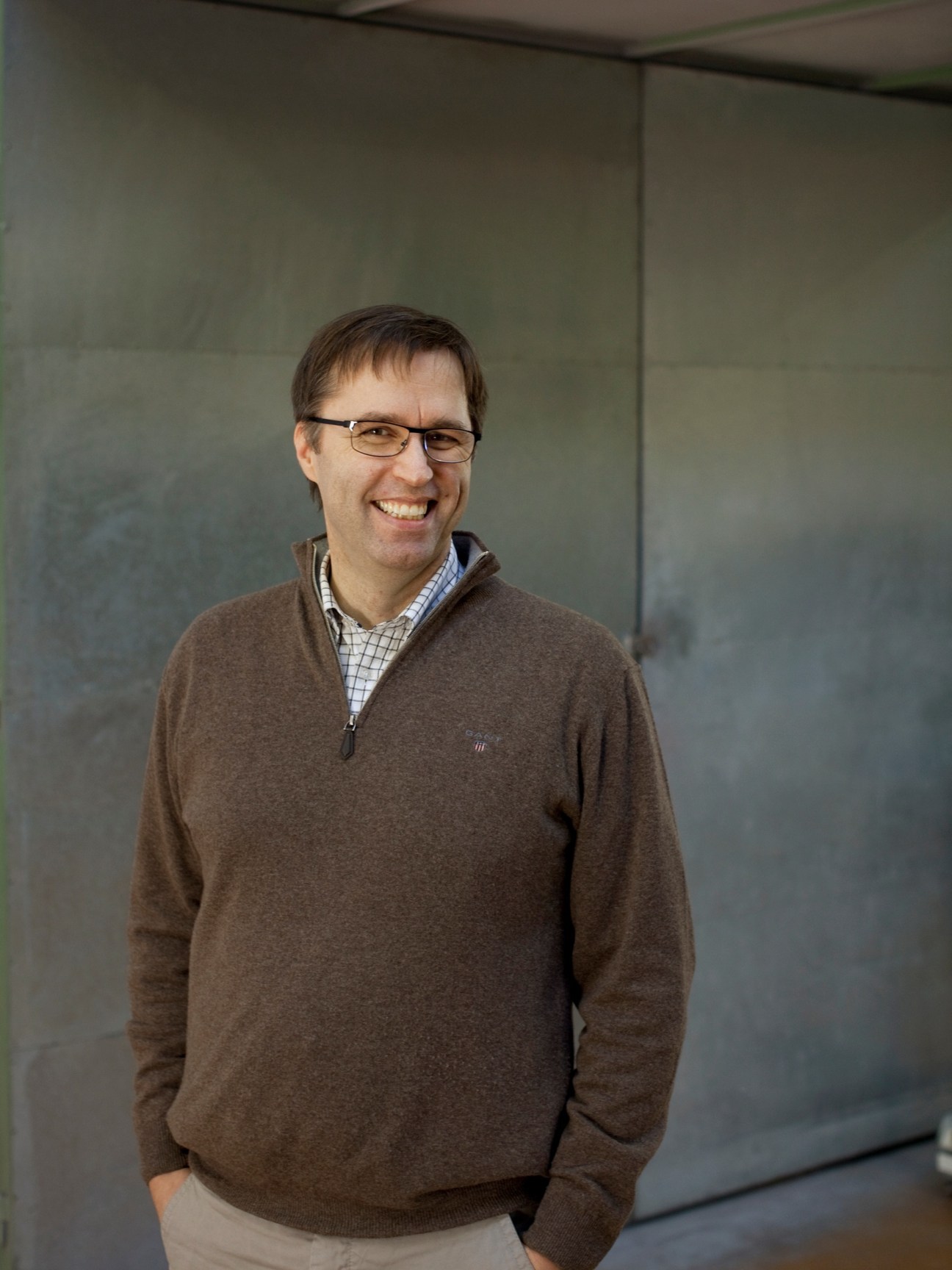 Thomas Schätti, CEO of Olympia, smiling at the camera in front of a grey wall.