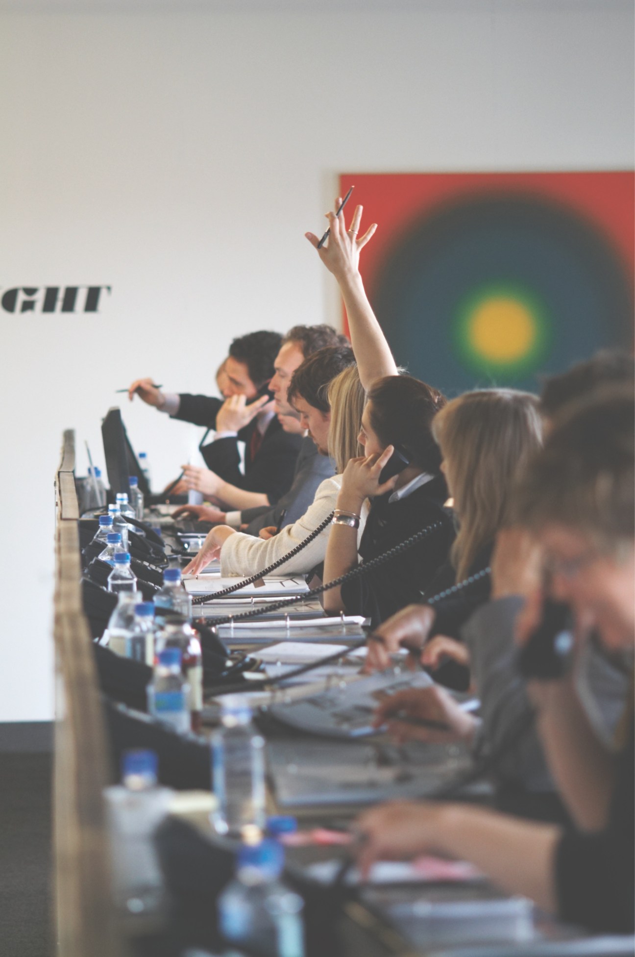 Phone bidders seated at a long desk with headsets and notepads during an auction.