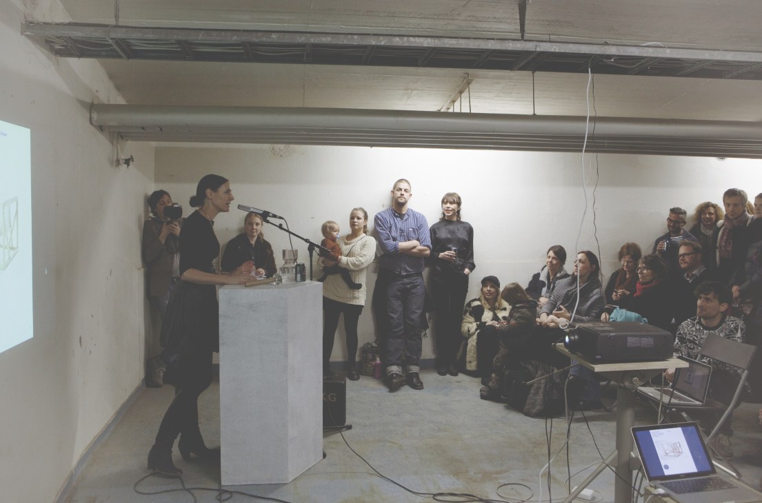 Young designers and attendees gather in a warehouse space for Örnsbergsauktionen's auction event in Stockholm.