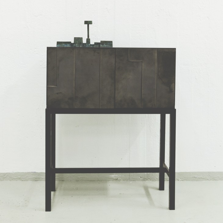 Bronze cabinet by Folkform with geometric paneled doors and a sculptural top element.