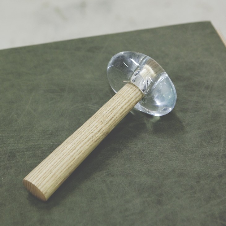 Hammer by Kristoffer Sundin with a clear glass head and light wood handle.
