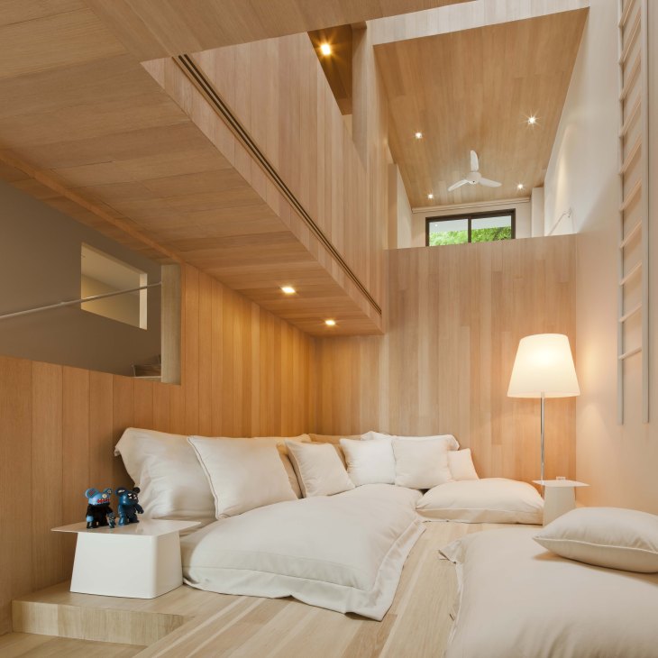 Wooden bedroom interior with bed, staircase, and Japanese Bearbrick figurines on nightstand