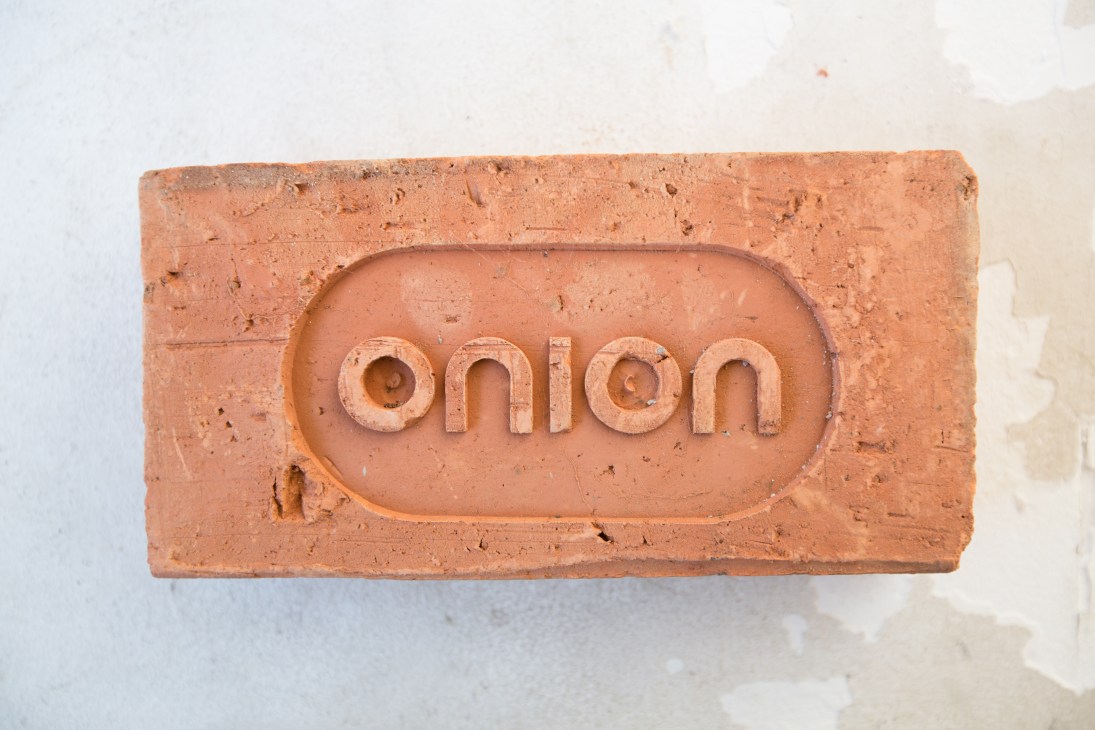 Custom-made terracotta brick with the Onion logo embossed in relief.