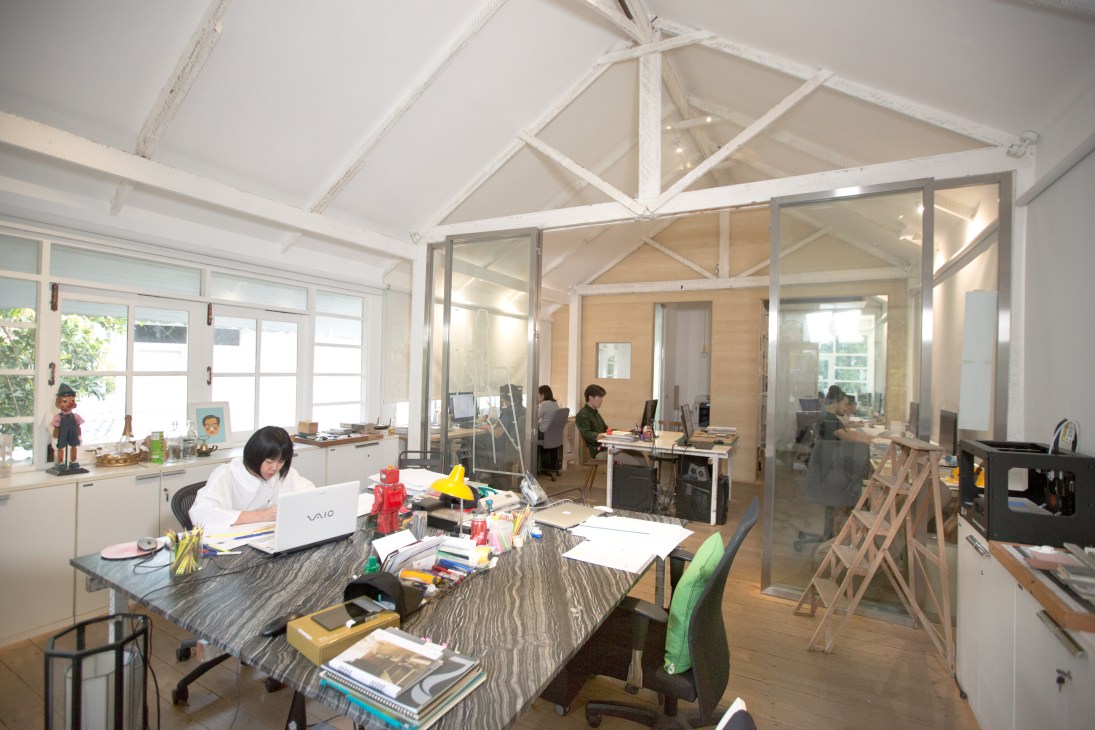 Arisara Chaktranon working at her desk in the bright, open Onion studio with her team visible in background offices.
