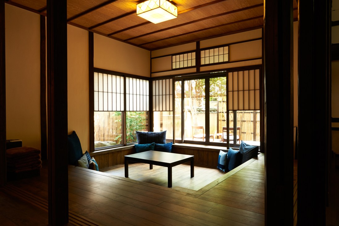 Traditional Japanese room with wooden beams, shoji screens, blue cushioned seating, low table and garden views at Minato no yado hotel.