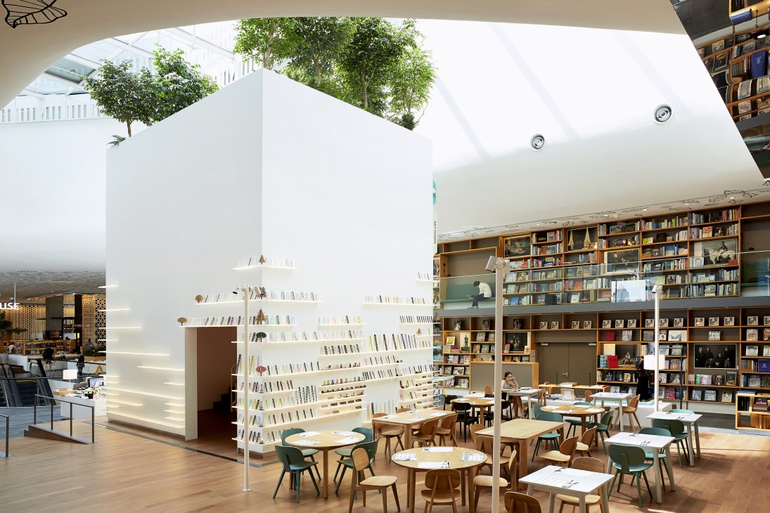 Interior of Open House at Central Embassy in Bangkok showing white shelving tower with books and seating areas with green chairs below