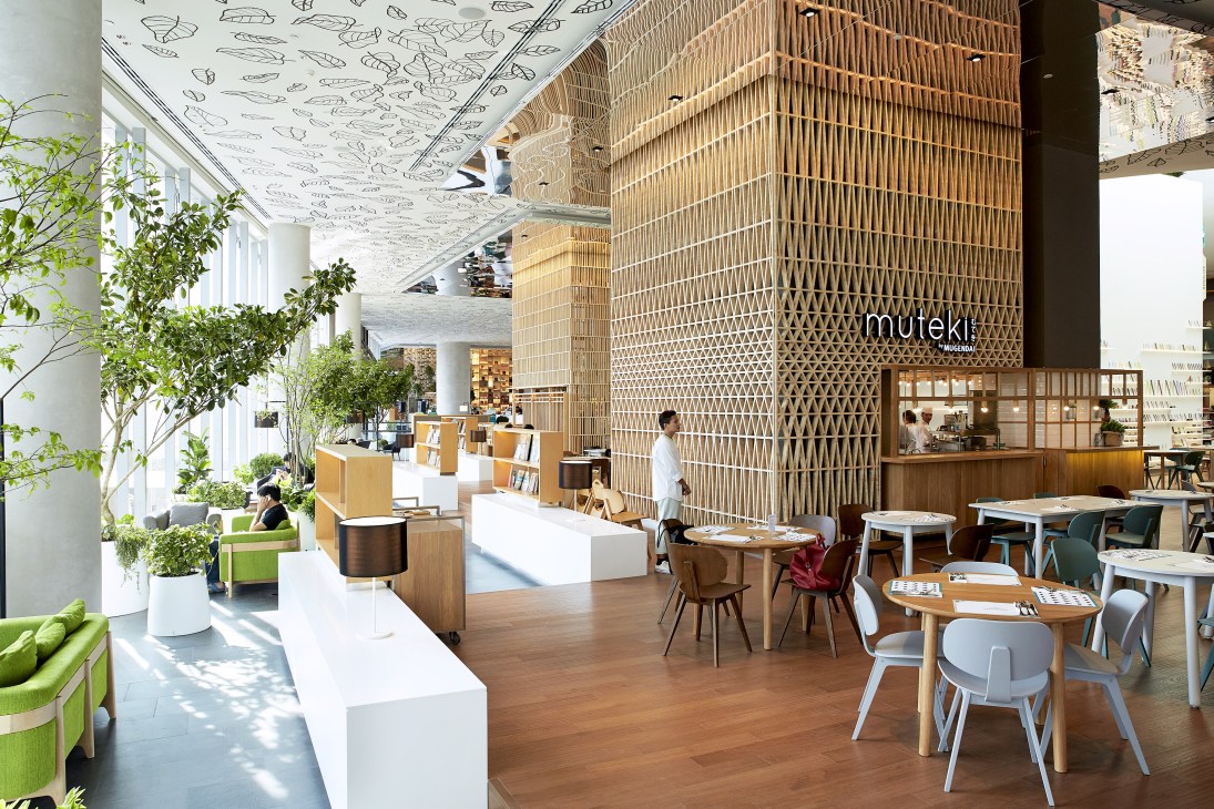 Open House restaurant interior with wooden furniture, tall woven wood partition wall, and patterned ceiling.