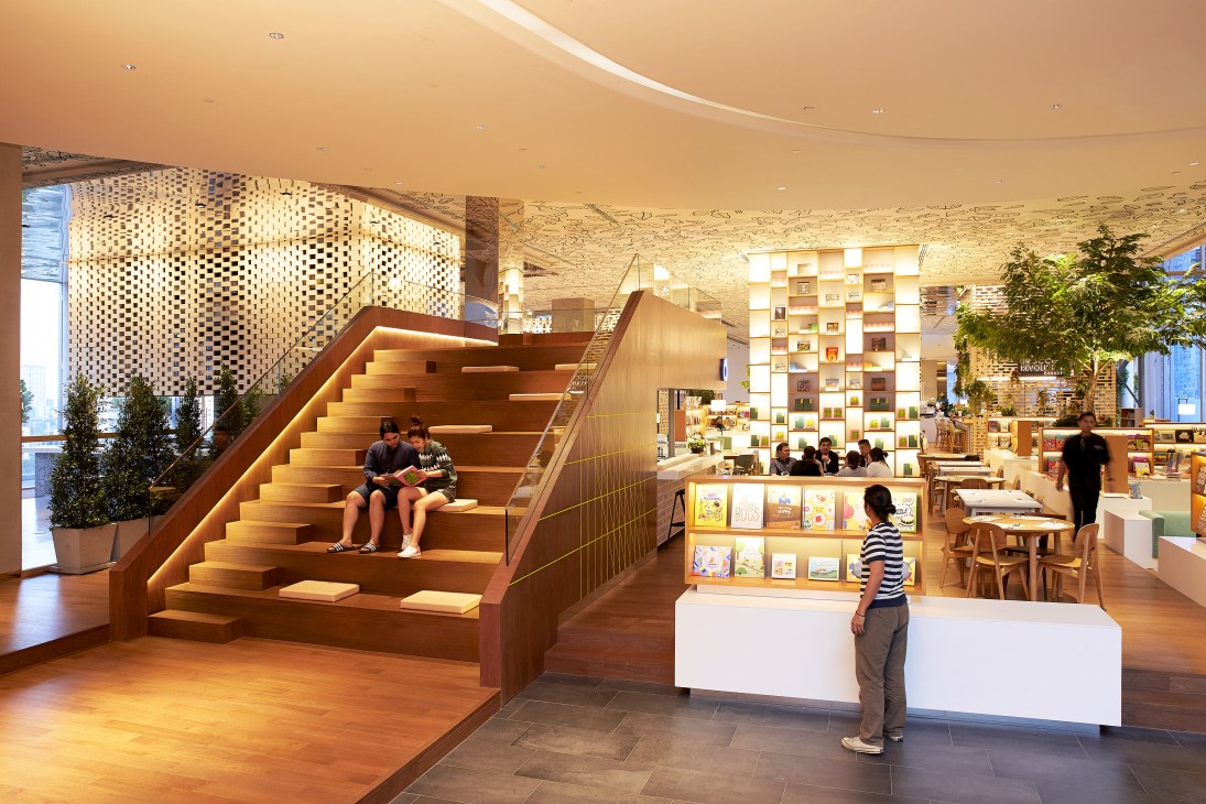 Wooden reading steps with integrated lighting in Open House Bangkok, with shelving and café areas visible in the background.