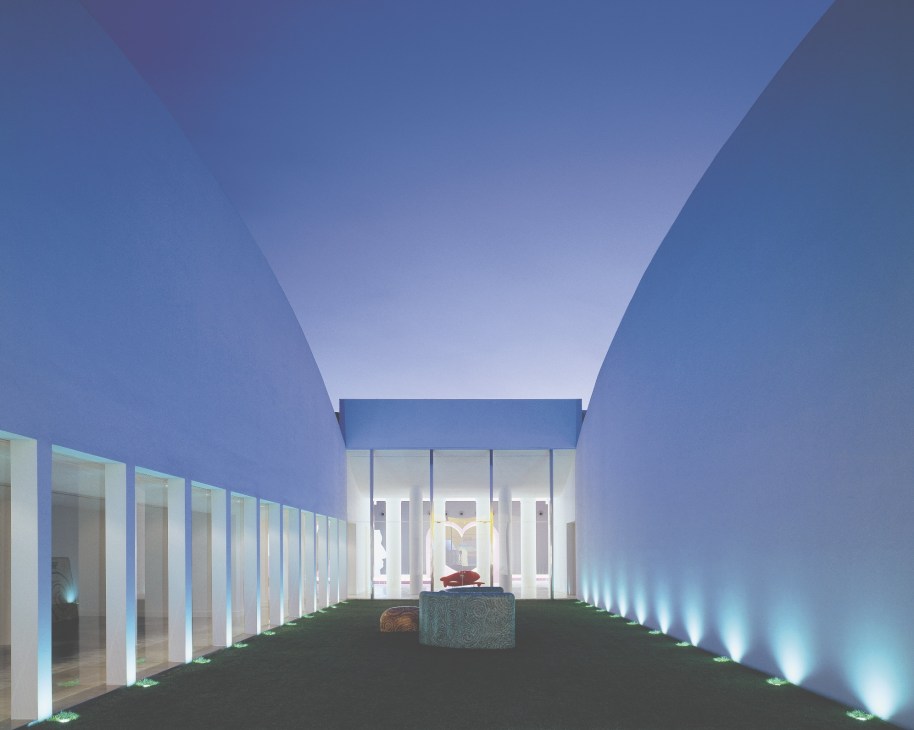 Interior of Bisazza Foundation with blue walls, glass-fronted rooms, and mosaic displays under dramatic lighting.