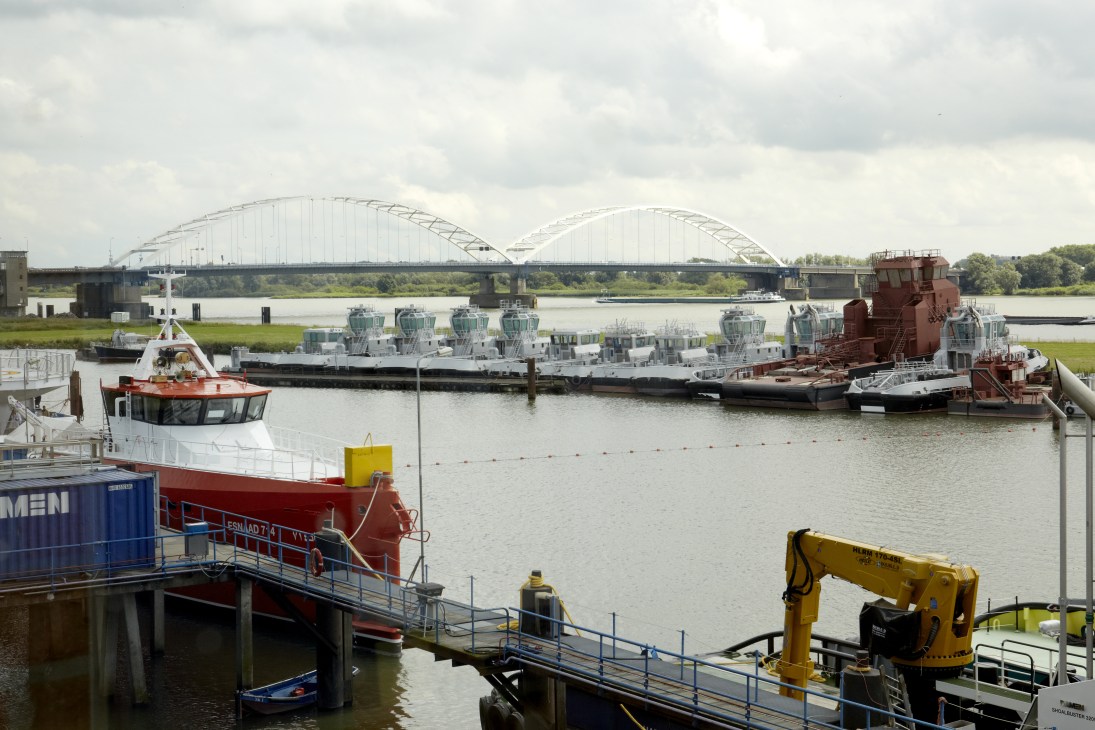 Multiple Damen patrol boat hulls moored at Gorinchem shipyard along the Merwede river.