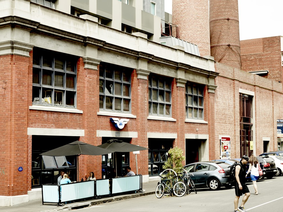 Converted brick factory building with modern street-level cafe and outdoor seating on Oxford Street, Collingwood.