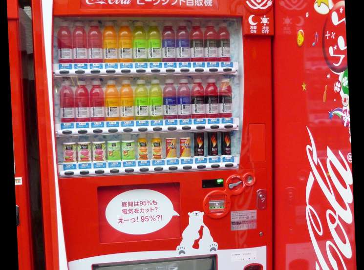 Red Coca-Cola peak shift vending machine with colorful promotional graphics and Japanese text on display.