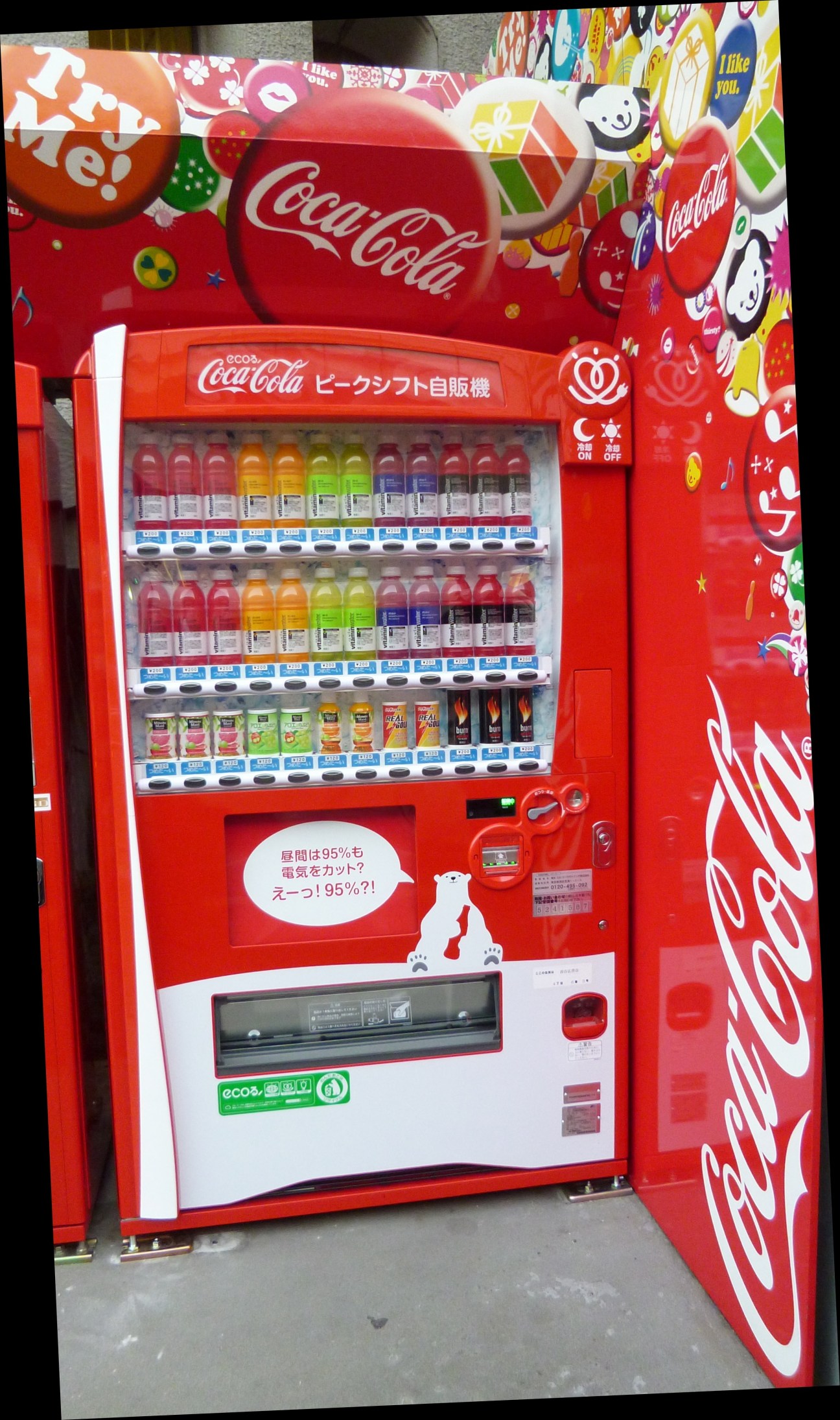 Red Coca-Cola peak shift vending machine with colorful promotional graphics and Japanese text on display.