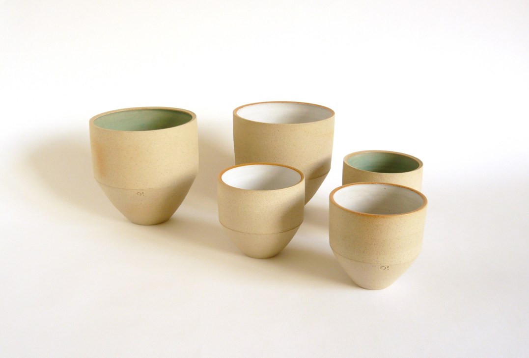 Five ceramic vessels by Pat O'Leary with cream exteriors and contrasting green and white interiors.