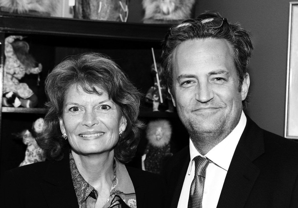 Black and white portrait of Alaska Senator Lisa Murkowski smiling at the camera next to a man in formal attire.