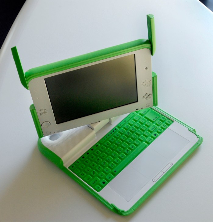 Green and white XO laptop with antenna handles and keyboard designed for children in developing regions.