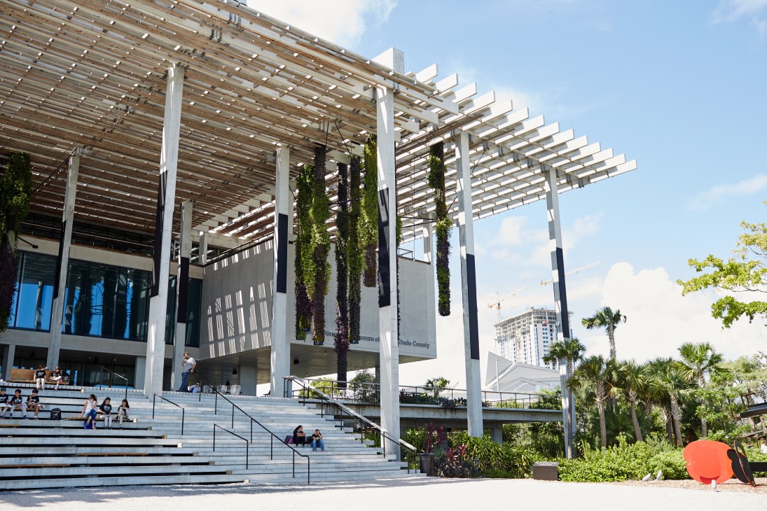 Exterior of Pérez Art Museum Miami with modern white pergola structure, wide steps, and hanging green plants.