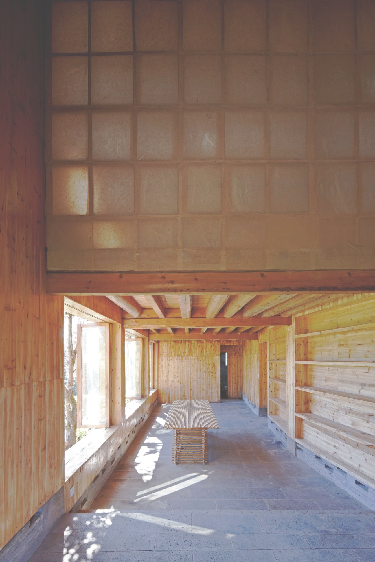 Interior of timber-constructed museum building with wooden walls, exposed beams, and large gridded windows allowing natural light.