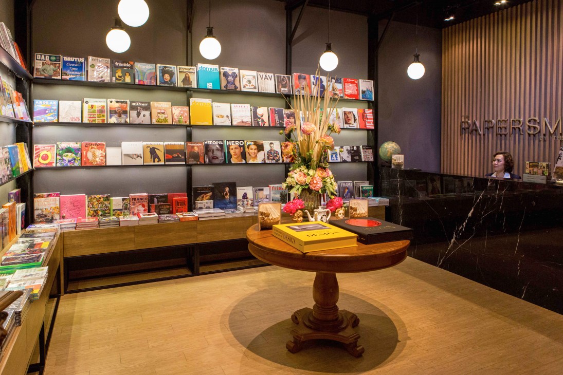 Modern magazine store with wood-paneled walls, spherical pendant lights, and shelves displaying colorful publications