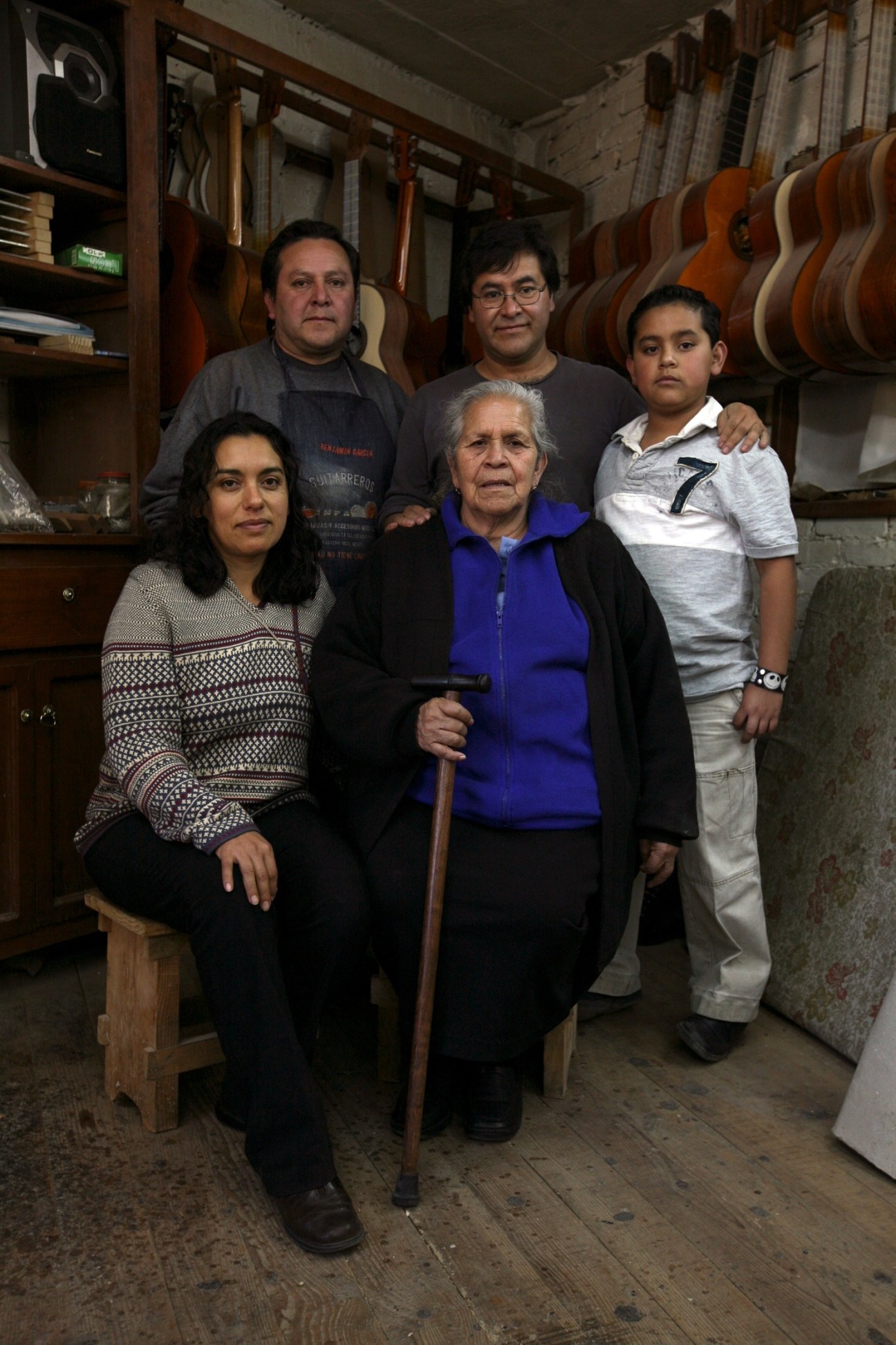 Abel García López (centre, back row) stands with his family in his guitar workshop surrounded by finished instruments.