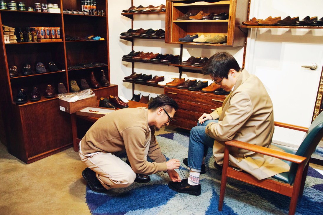 A shoe fitter helps a customer try on handmade shoes at Parlour, a high-end men's shoe shop in Seoul.