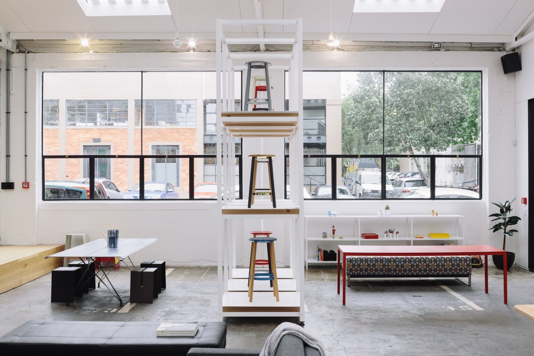 IMO design firm's showroom in a converted industrial space with white walls, large windows, and modern furniture displays.