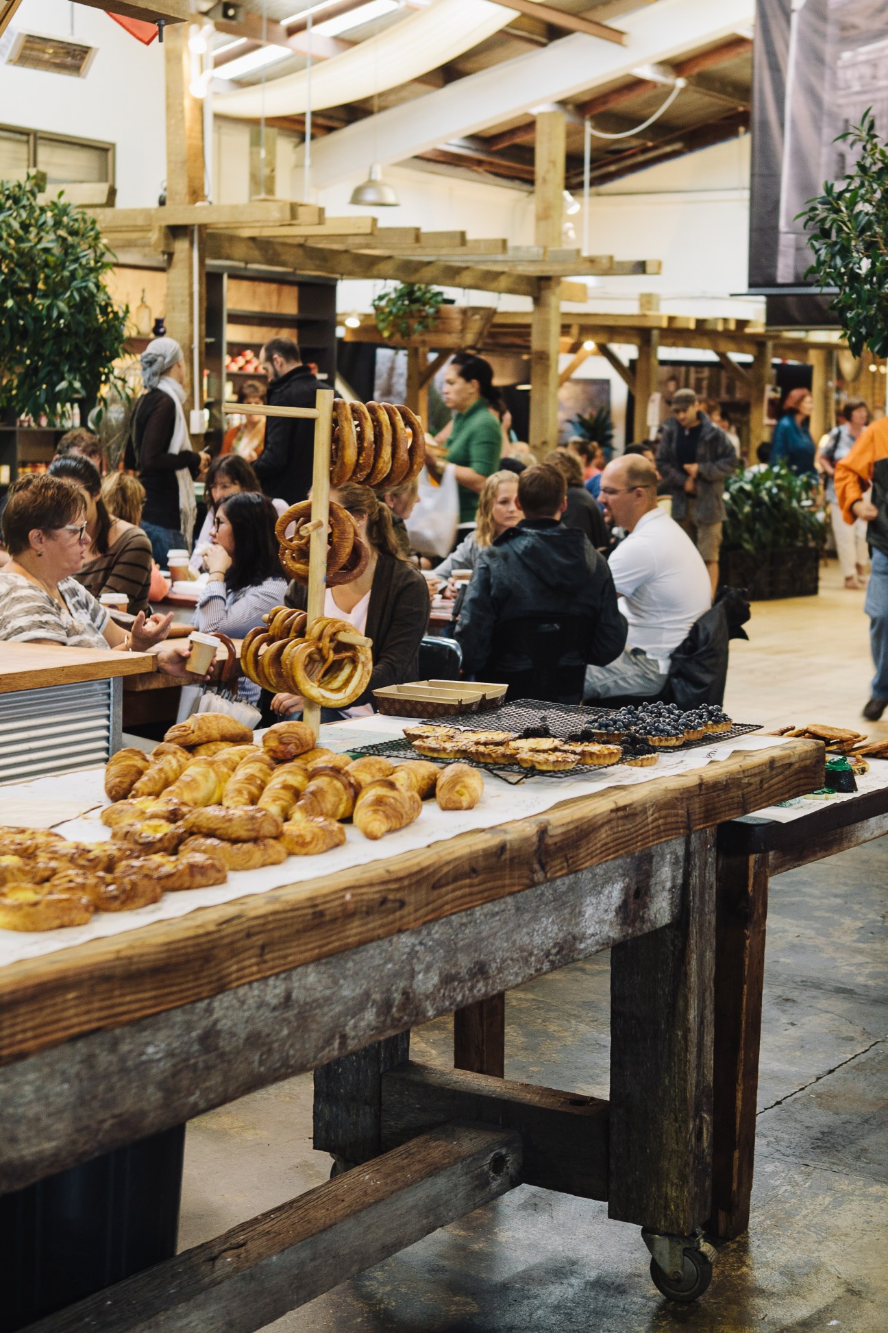 Display of fresh bread and pretzels at La Cigale bakery counter with customers in background.