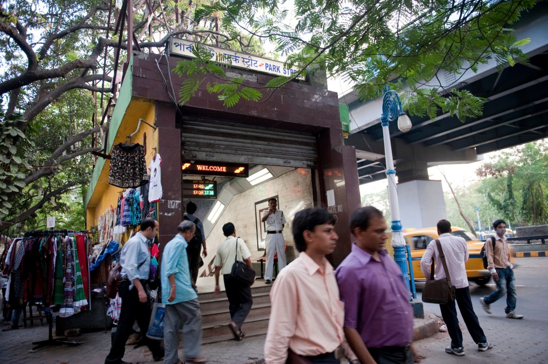 Park Street metro stop entrance in Kolkata with pedestrians and street vendors outside.