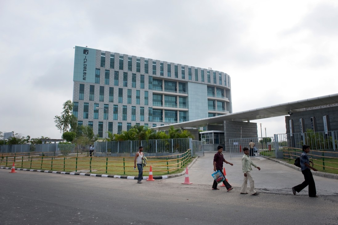 Modern multi-story office building with glass facade in Rajarhat, Kolkata, with pedestrians walking in foreground.