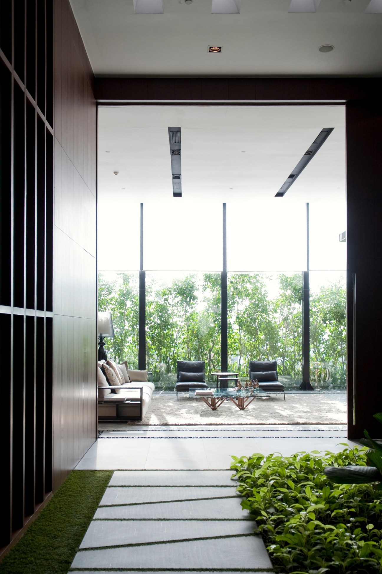 Modern showroom interior with floor-to-ceiling windows overlooking landscaped grounds and contemporary furniture.