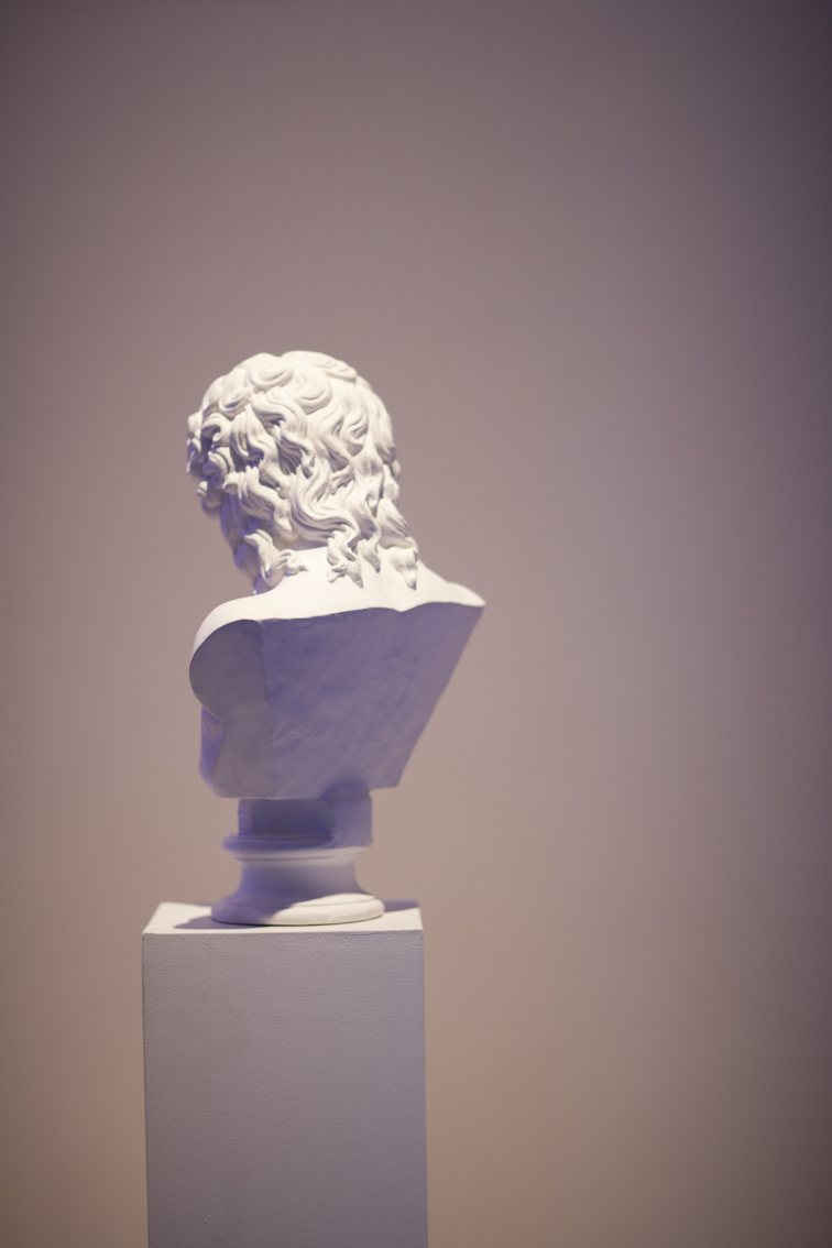 White classical marble bust sculpture displayed on a pedestal against a neutral background.