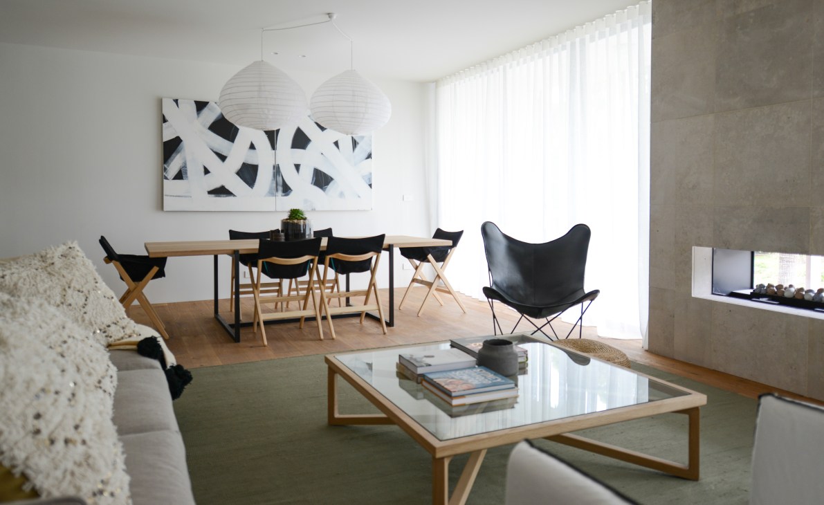 Modern hotel penthouse interior with dining table, black chairs, white pendant lights and abstract wall art.