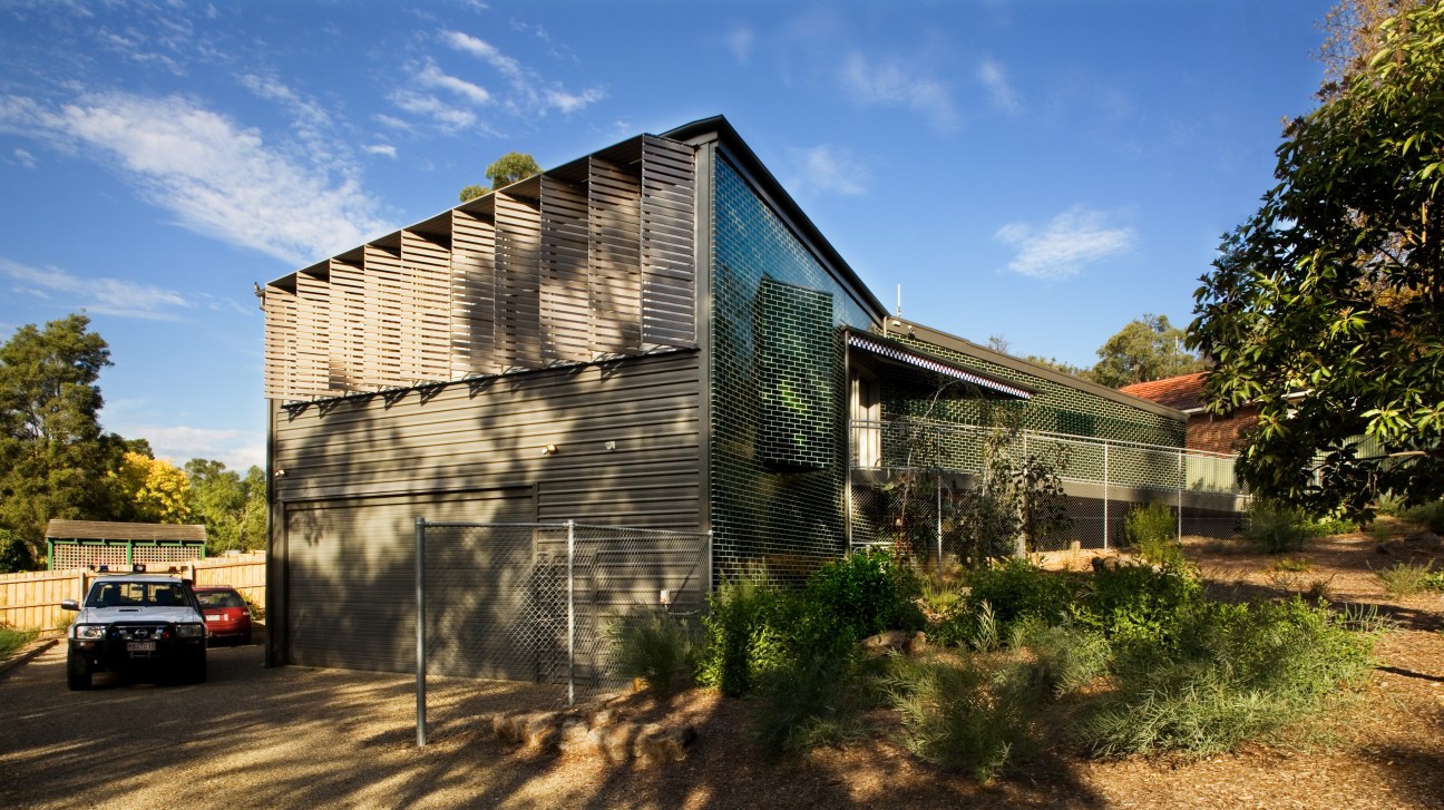 Warrandyte police station with green brick exterior and horizontal louver detailing nestled in bushland.