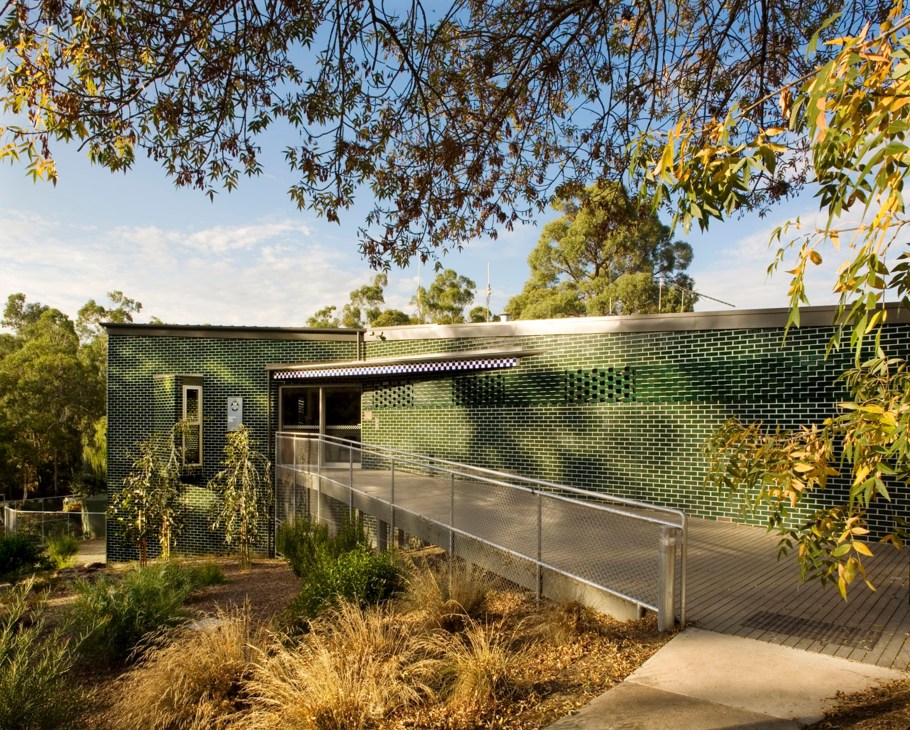 Warrandyte police station exterior with green brick walls nestled in bushland with native vegetation.