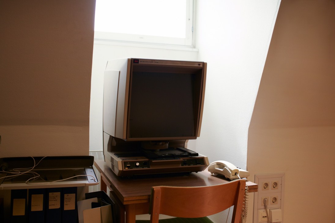Vintage microfiche reader machine on wooden desk with chair in SIPRI library.