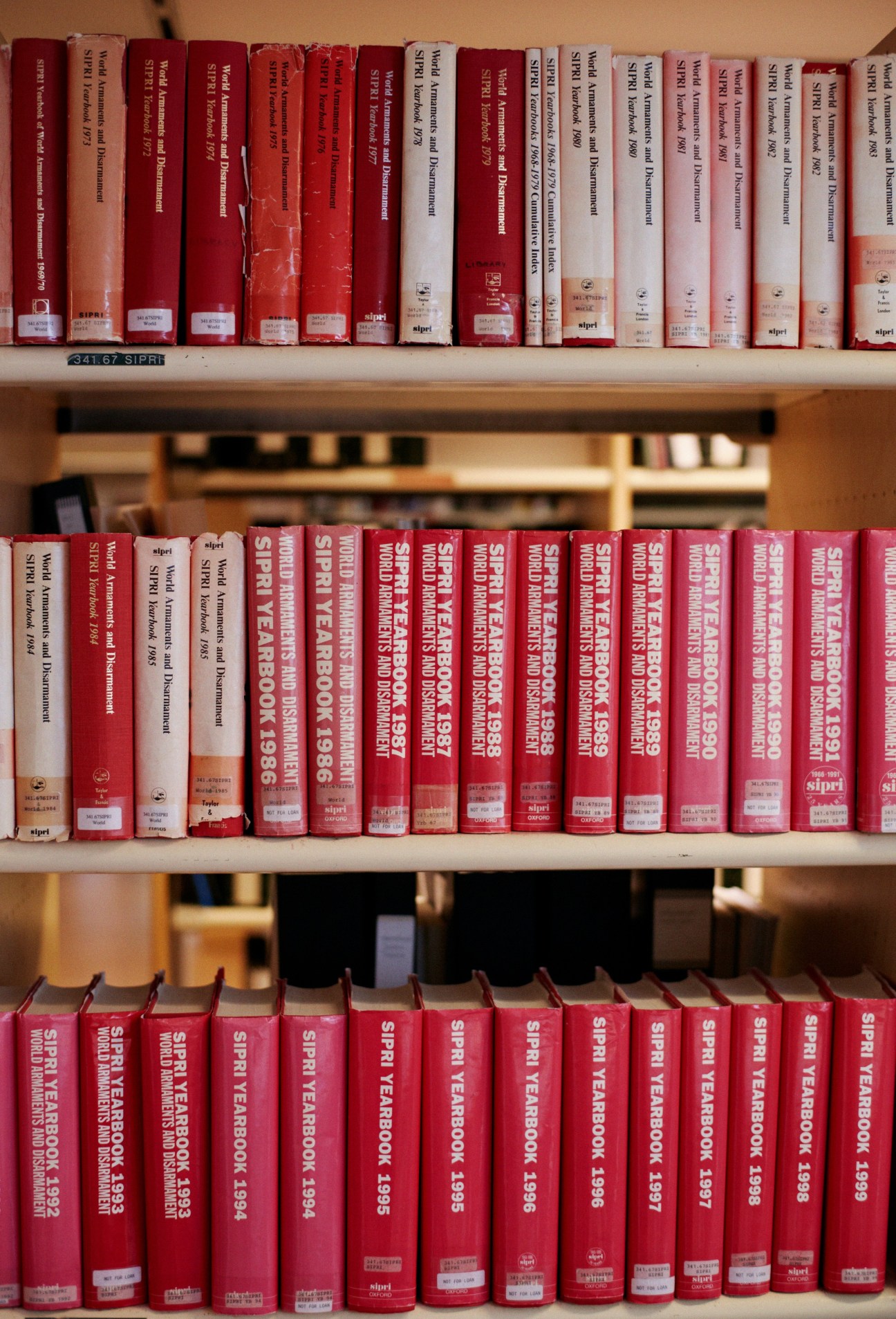 SIPRI yearbooks in red spines arranged on library shelves, spanning multiple decades of publications.