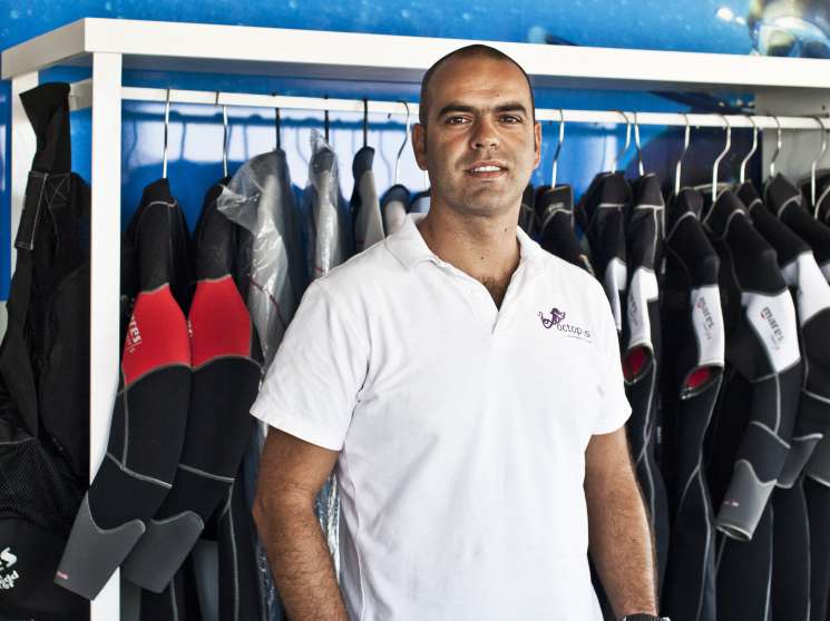 Pedro Freixo stands in front of diving equipment and an Octopus scuba shop sign in Luanda.
