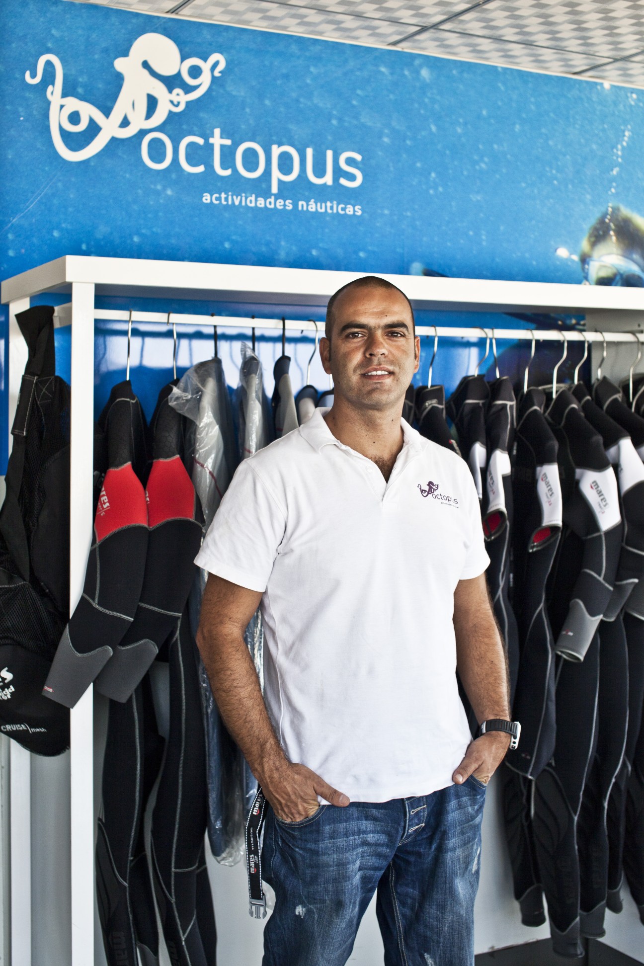 Pedro Freixo stands in front of diving equipment and an Octopus scuba shop sign in Luanda.