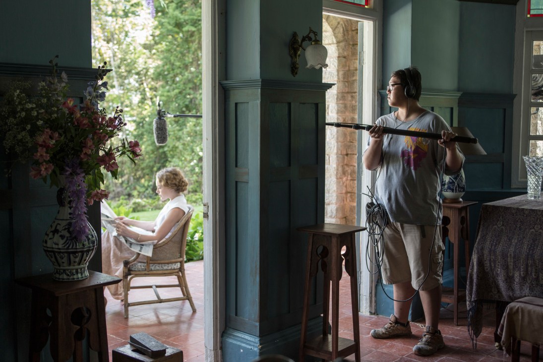 Boom operator holds microphone on set of Indian Summers with actress visible through doorway