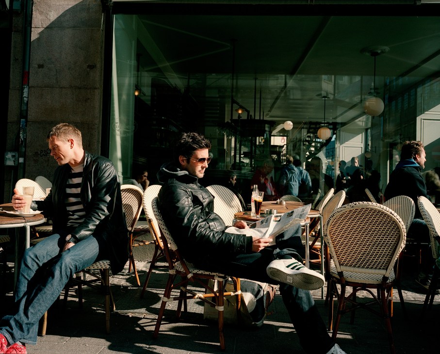 People seated at outdoor café tables on a sunny Copenhagen street.