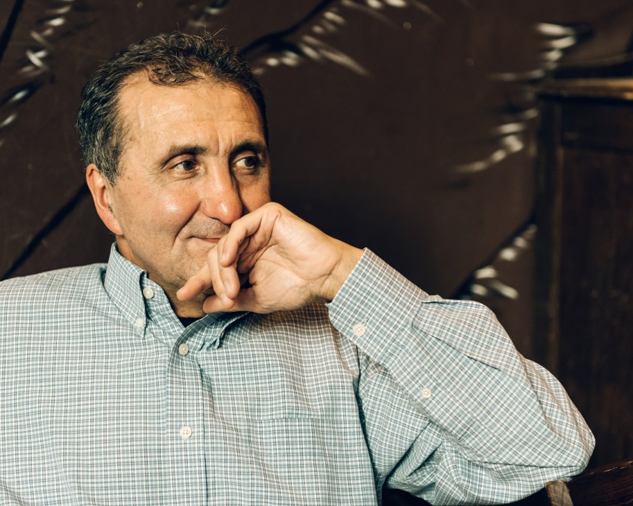 Pete Souza, former White House photographer, poses in contemplative pose wearing a checkered shirt.