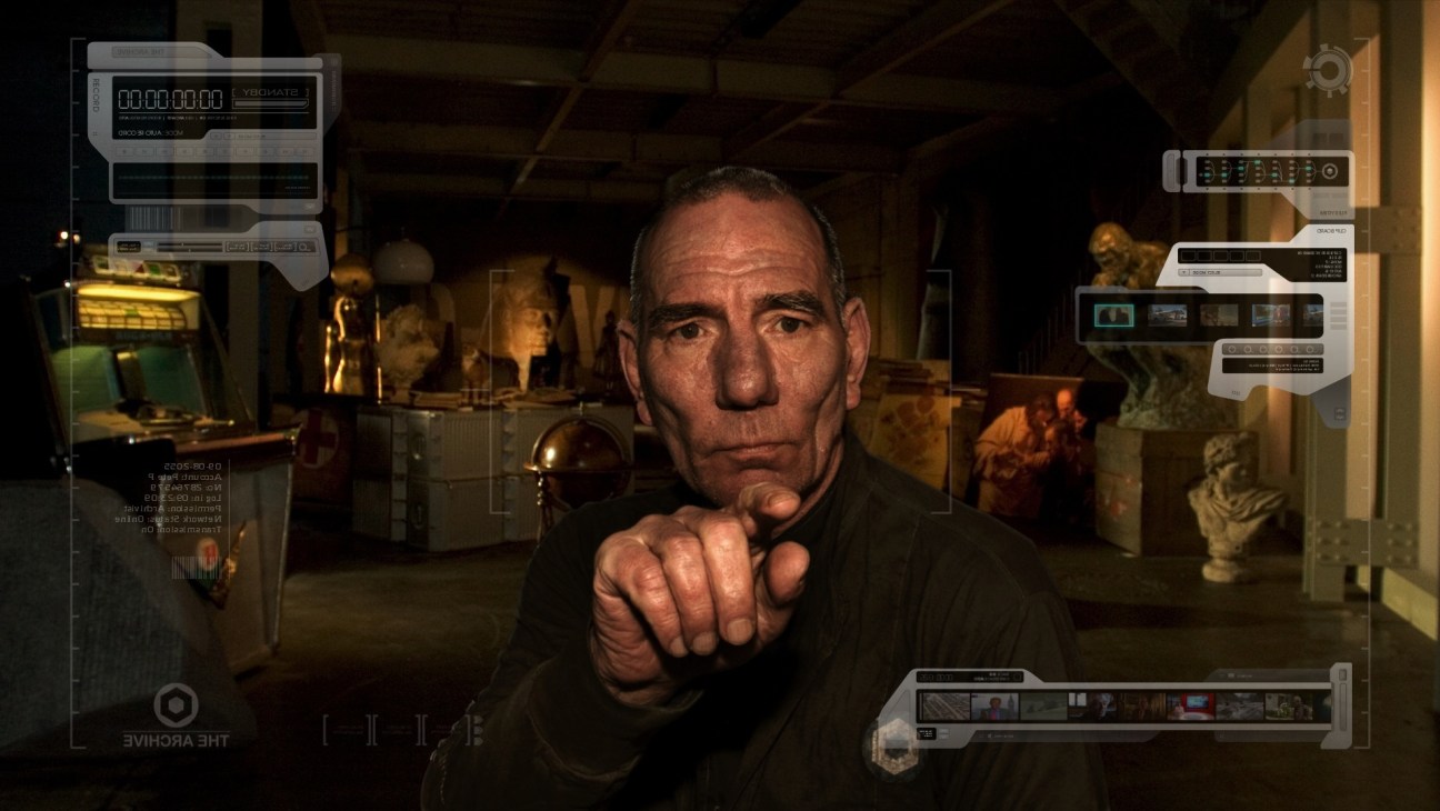 Pete Postlethwaite in a futuristic setting surrounded by screens and technology in The Age of Stupid.
