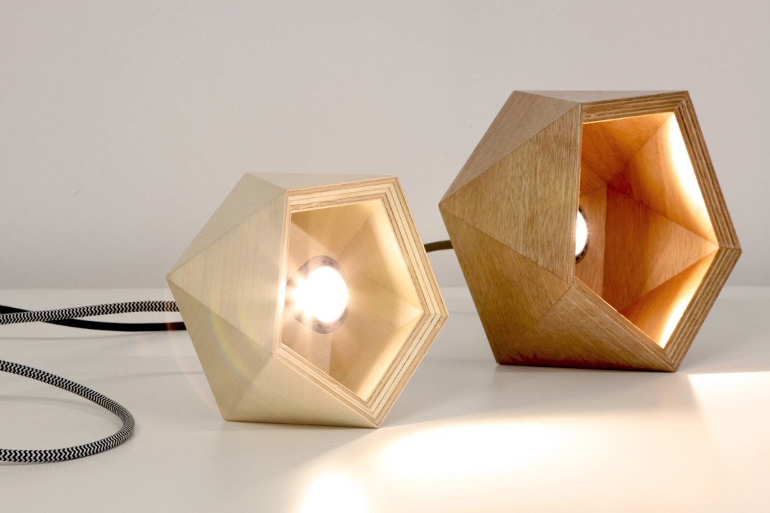 Two wooden hexagonal lamps with illuminated interiors and fabric cords, by Here Design.