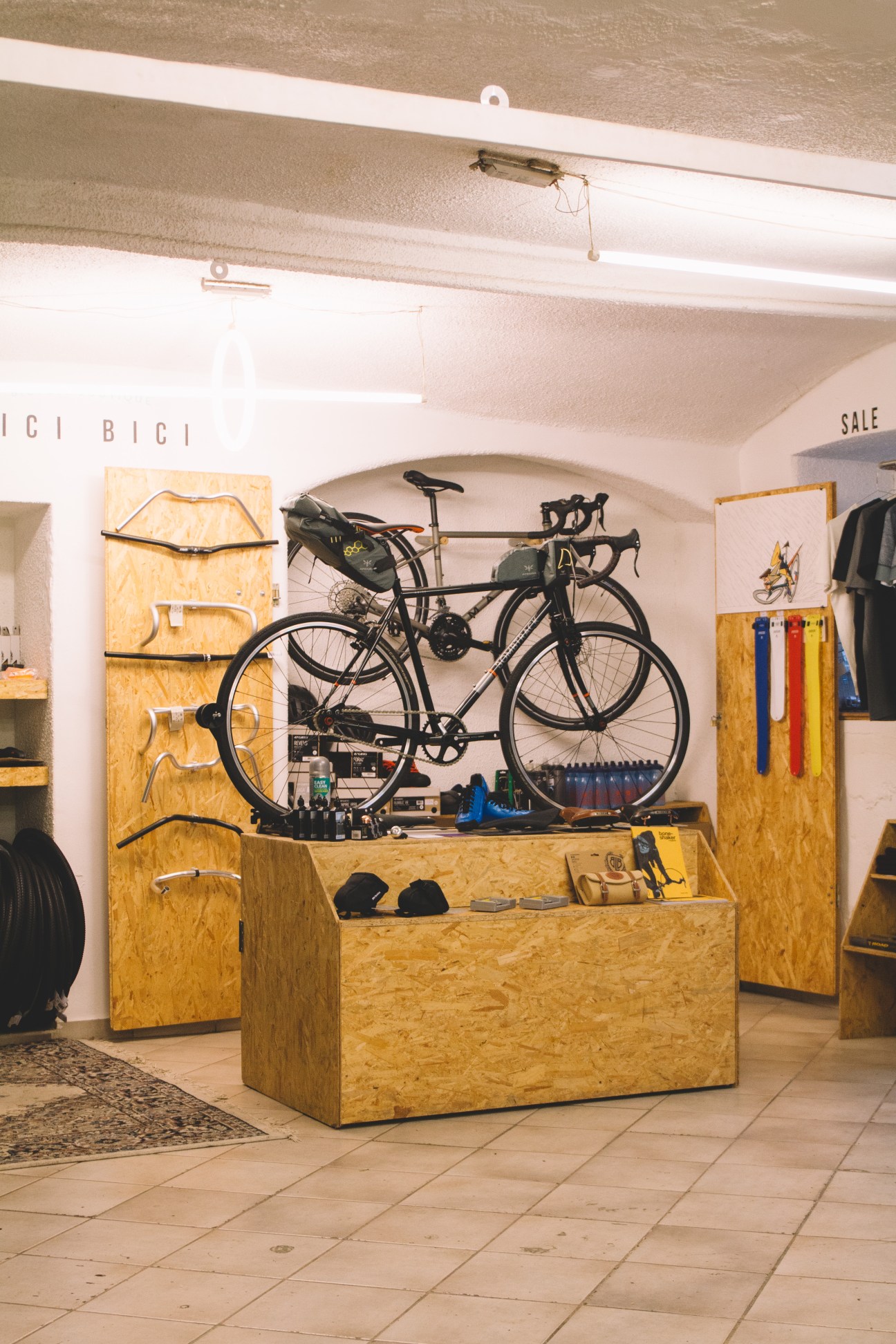 Pici Bici bike shop interior with bicycles displayed on wooden wall and central counter with components.
