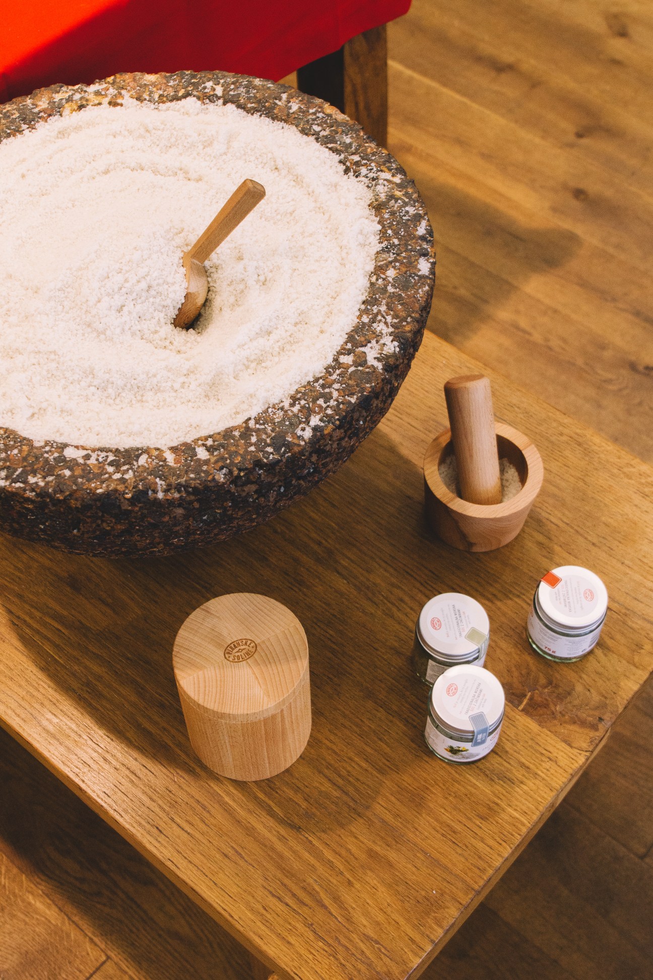 Salt harvested from Piranske Soline displayed with wooden tools and small containers on a wooden surface.