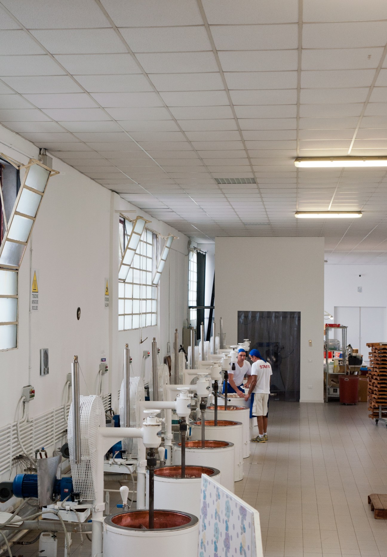 Large copper cooking vats with nougat mixture inside line the Scaldaferro factory floor.